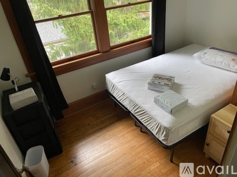 A bedroom with a bed, nightstand, and window.