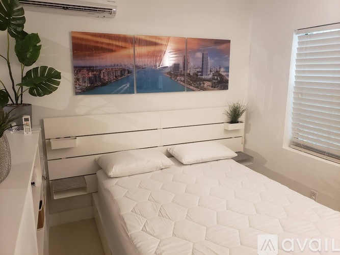 A bedroom with a large bed and a picture of a city skyline on the wall.