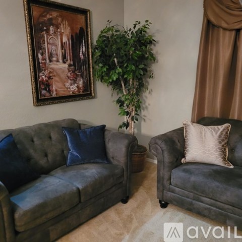 A living room with two grey couches and a framed painting on the wall.