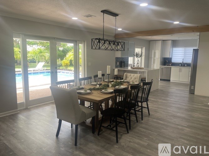 A dining room with a table set for six and a pool outside the window.