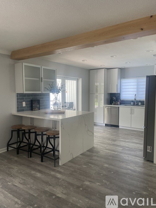 A kitchen with a bar area and a dining area in the background.