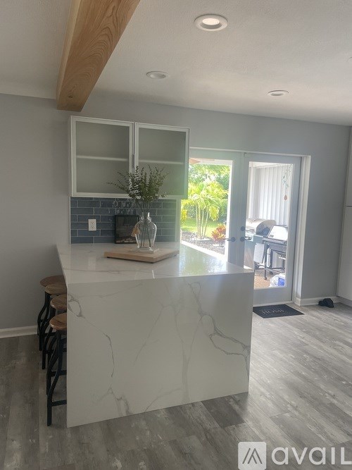 A kitchen with a marble countertop and a wooden bar stool.