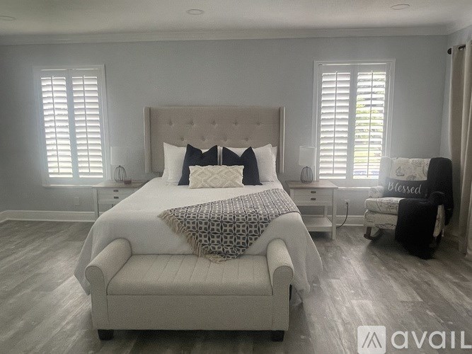 A bedroom with a large bed and a chair.