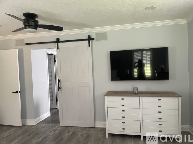 A room with a white cabinet, a ceiling fan, and a sliding door.