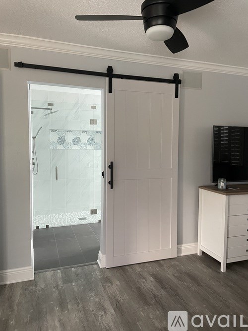 A white door with a black handle and a fan above it.