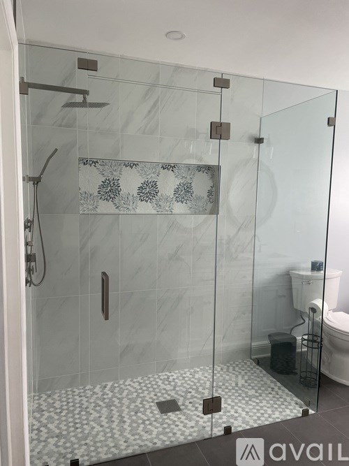 A bathroom with a glass shower door and a white toilet.
