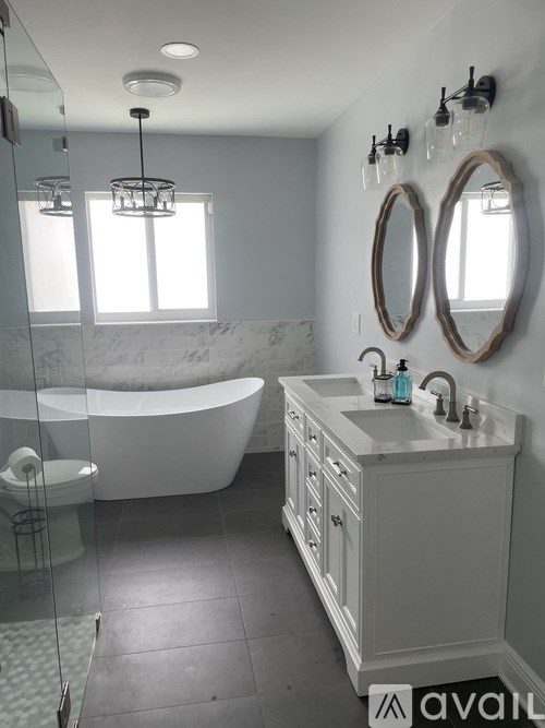 A bathroom with a tub, sink, and mirror.