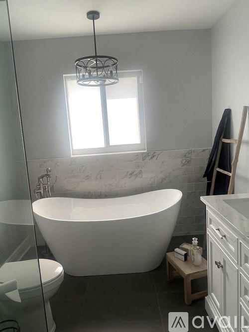 A white bathtub is in a bathroom with a window.