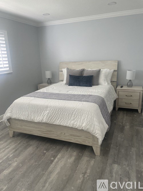 A bedroom with a large bed and two nightstands.