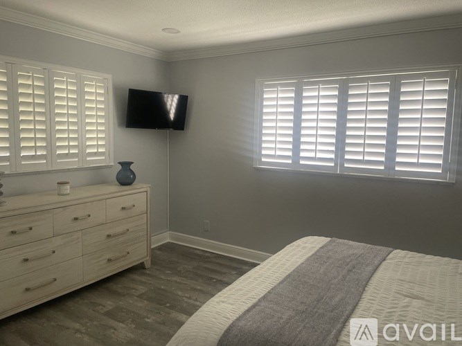 A bedroom with a bed, dresser, and a flat screen TV mounted on the wall.