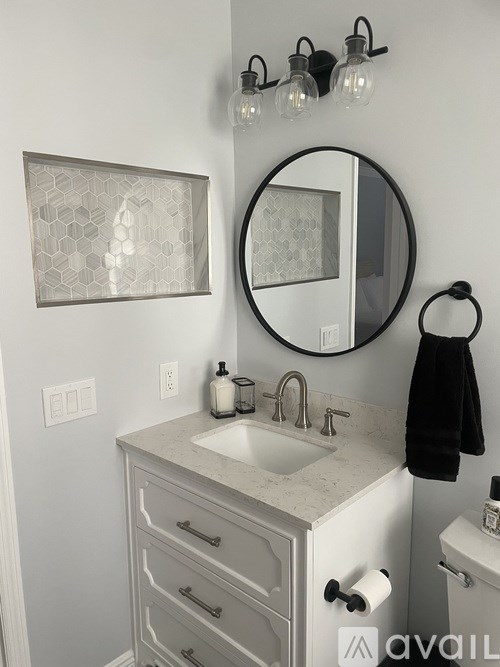 A bathroom with a sink, mirror, and light fixture.