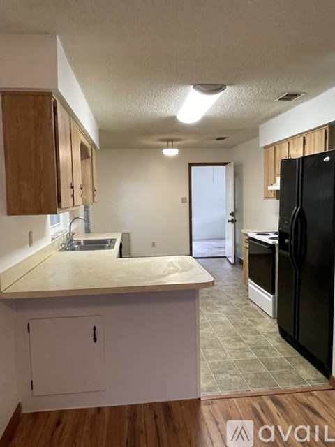 A kitchen with wooden cabinets and a black refrigerator.