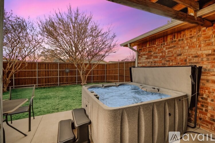 A hot tub is on a patio with a table and chairs.