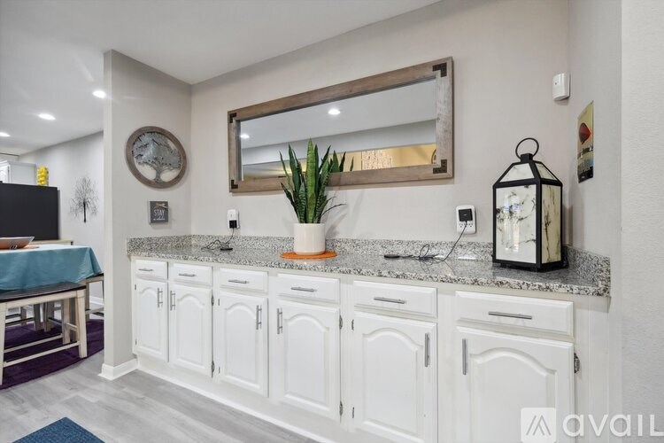 A kitchen with white cabinets and a large mirror above the counter.