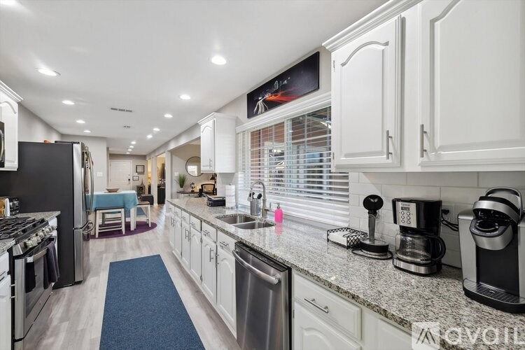 A modern kitchen with white cabinets and stainless steel appliances.