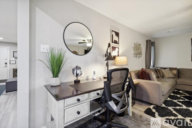 A modern home office with a desk, chair, and mirror.