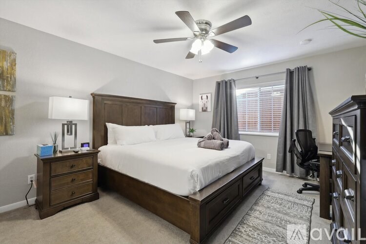A bedroom with a large bed, a dresser, and a ceiling fan.
