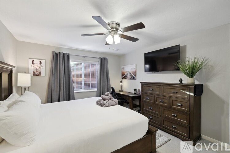 A bedroom with a bed, dresser, and a ceiling fan.