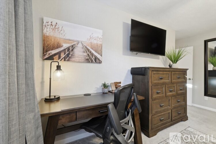 A room with a desk, chair, and a painting on the wall.