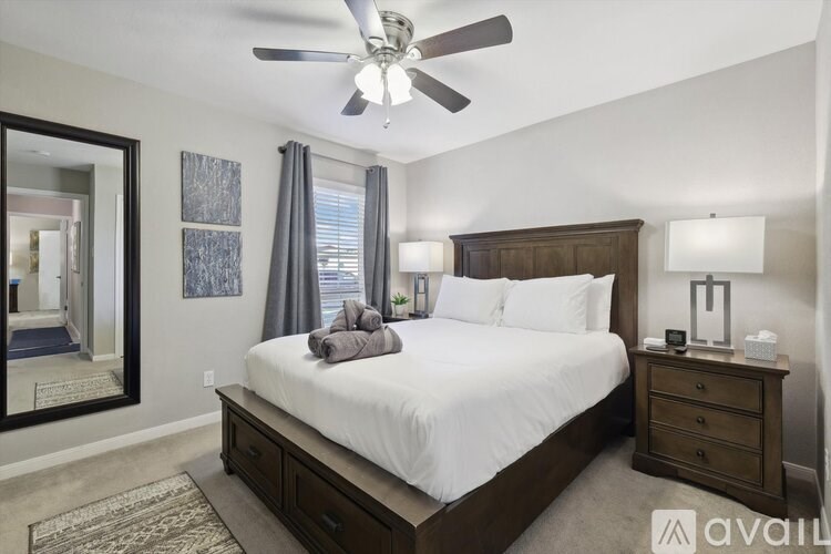 A bedroom with a bed, nightstand, and a ceiling fan.