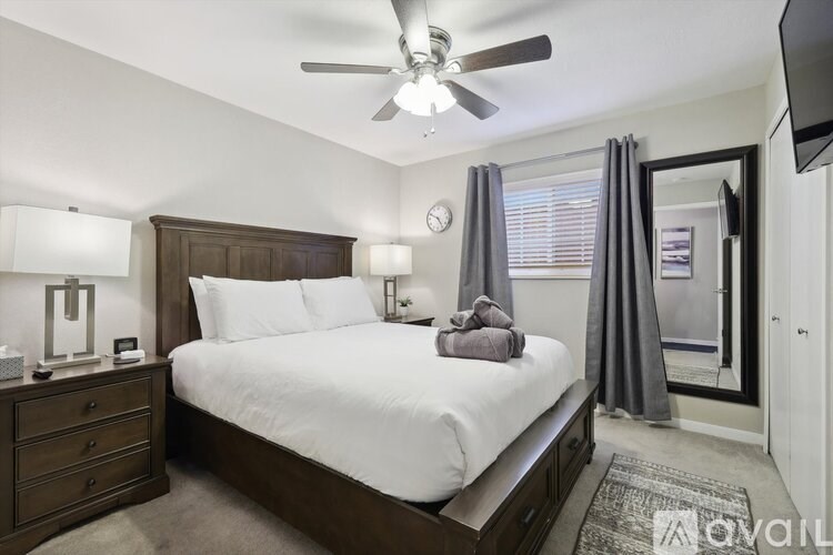 A bedroom with a bed, nightstand, and a ceiling fan.
