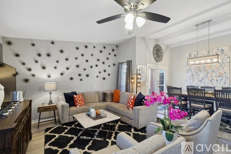 A living room with a couch, chairs, and a ceiling fan.