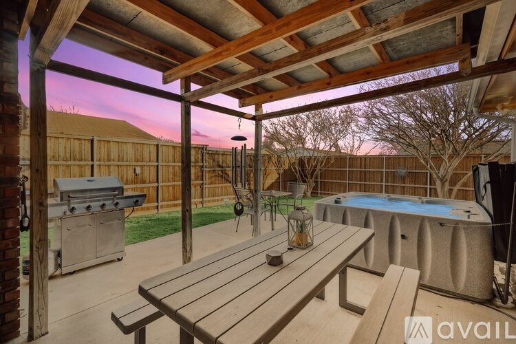 A wooden table is on a patio with a hot tub and grill in the background.