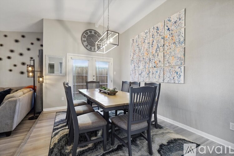 A dining room with a table set for four and a large painting on the wall.