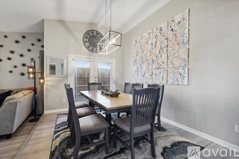 A dining room with a table set for four and a large painting on the wall.