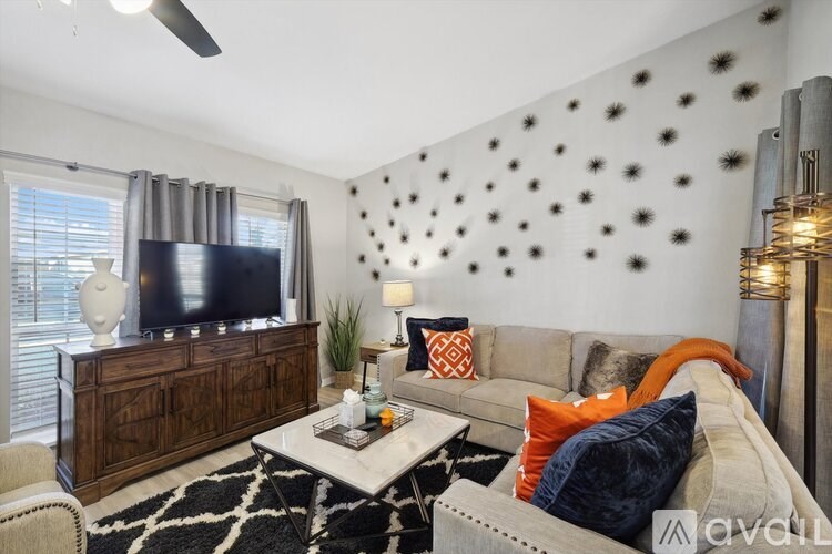 A living room with a grey couch, a coffee table, a television, and a wall with black dots.