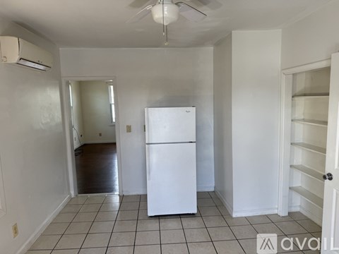 A white refrigerator in a kitchen with white walls and tile flooring.