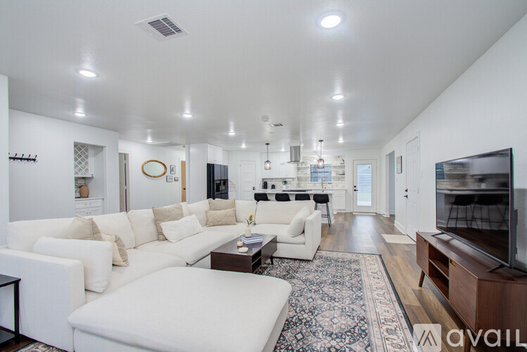 A spacious living room with white furniture and a rug.
