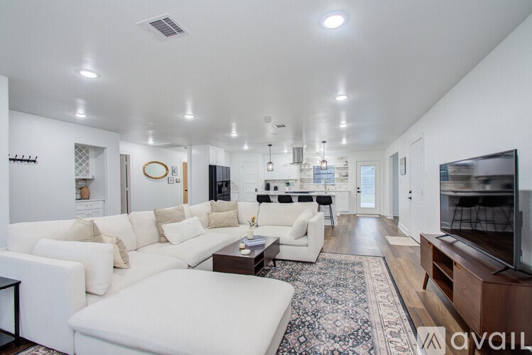 A spacious living room with white furniture and a rug.