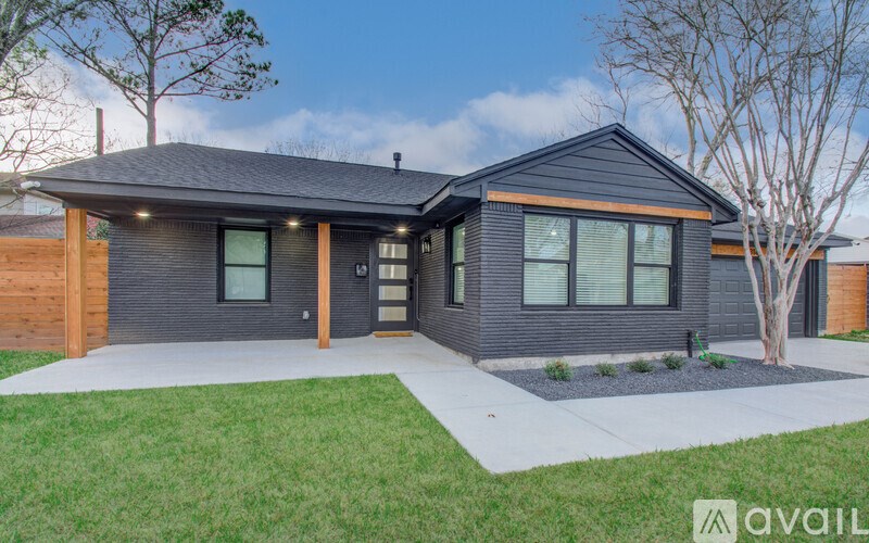 A modern house with a dark grey exterior and a large front yard.