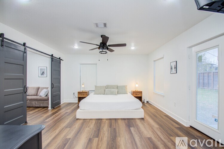 A bedroom with a bed, a couch, and a ceiling fan.