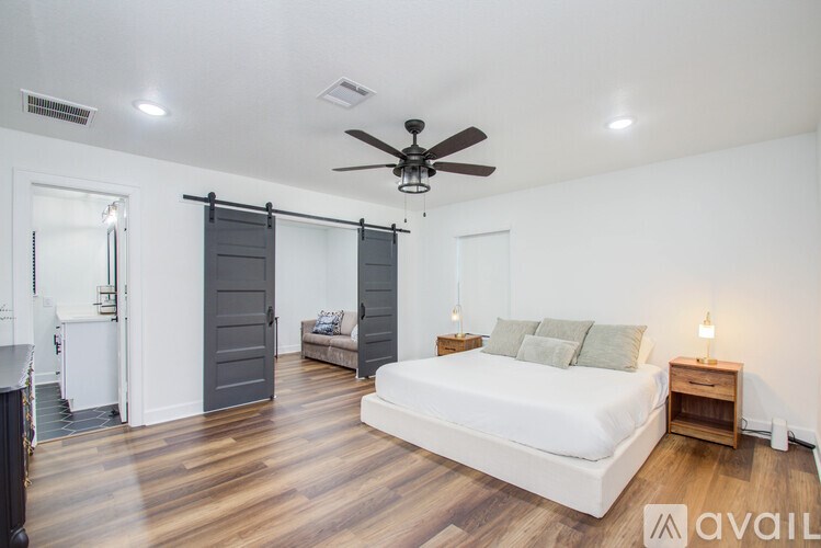 A bedroom with a bed, nightstand, and sliding doors.