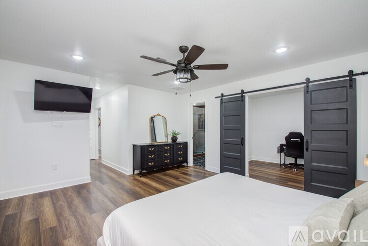 A bedroom with a bed, dresser, and sliding doors.