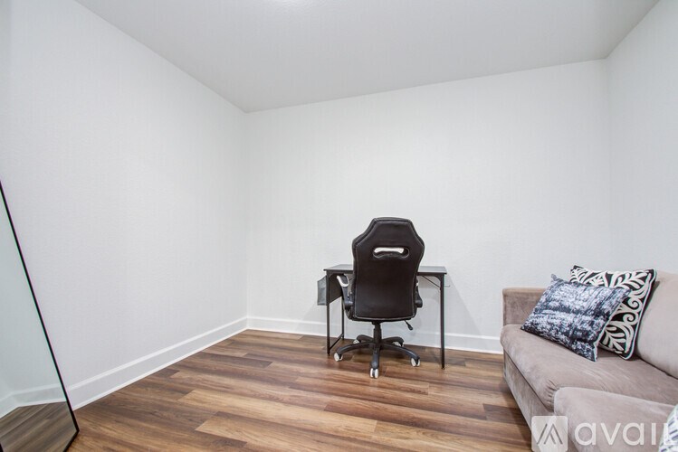 A room with a black chair and a couch with pillows.