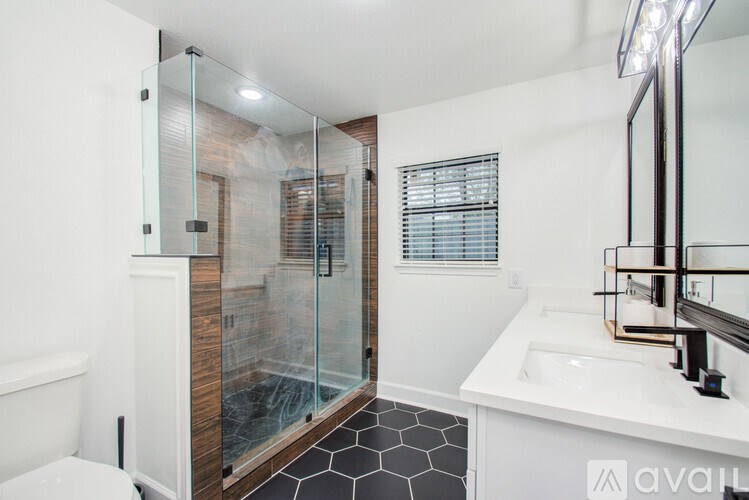 A bathroom with a white sink, a glass shower door, and a white toilet.