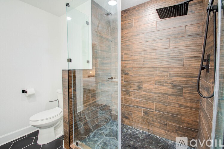 A bathroom with a toilet, a glass shower door, and a wooden wall.