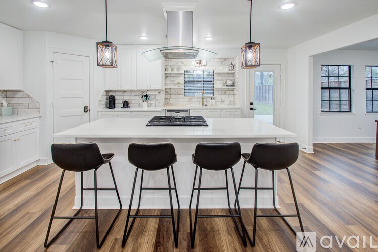 A modern kitchen with a white island and black barstools.