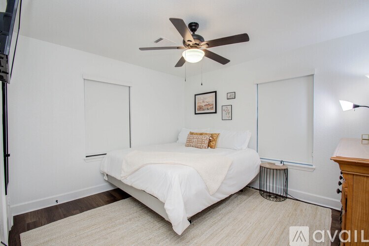 A bedroom with a white bed and a ceiling fan.