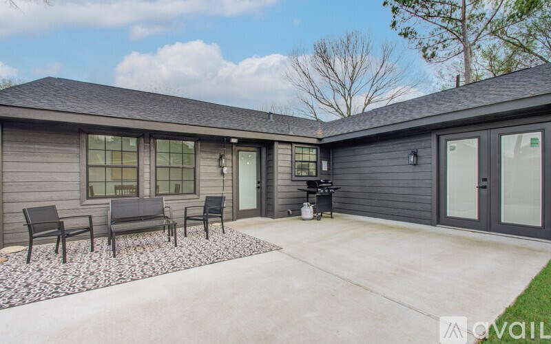 A house with a grey exterior and a patio with four chairs.