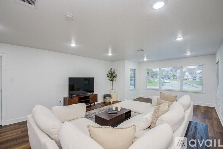 A living room with white furniture and a flat screen TV.