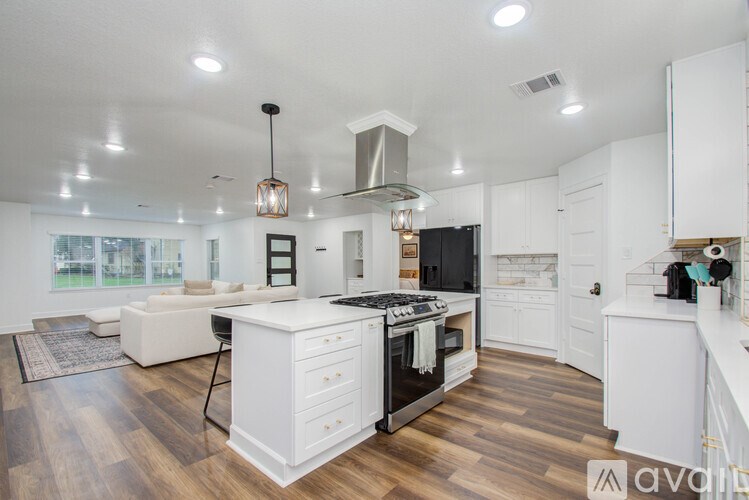 A modern kitchen with white cabinets and a wooden floor.