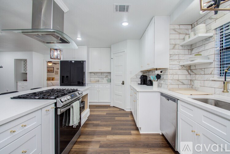 A modern kitchen with white cabinets and a black stove top.