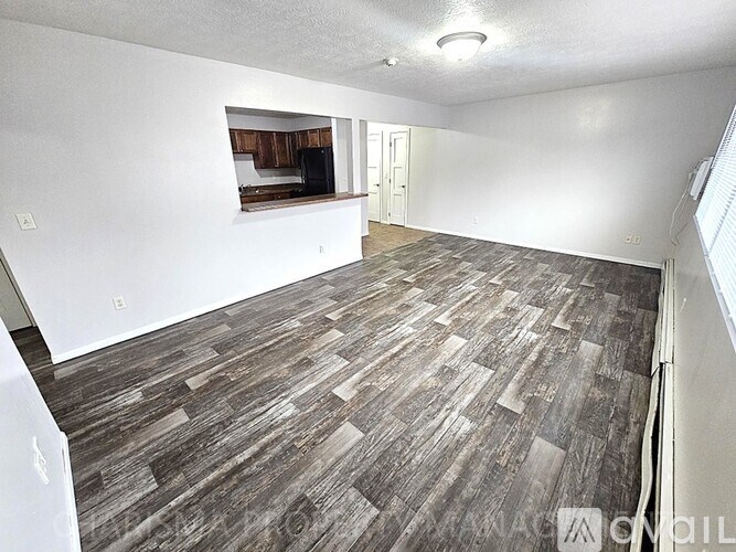 A room with a wooden floor and a window on the right side.