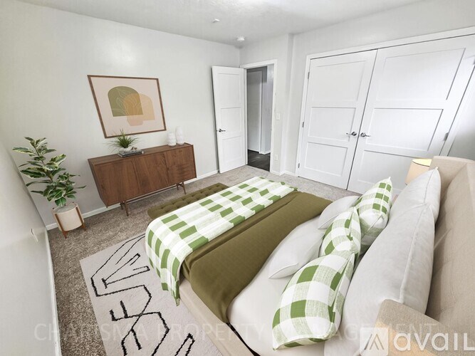 A bedroom with a bed covered in a green and white checkered blanket.