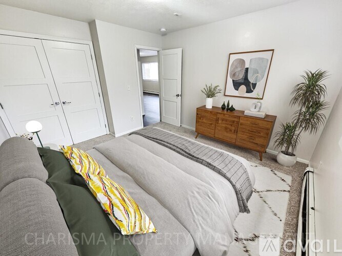 A bedroom with a bed, a dresser, and a plant.