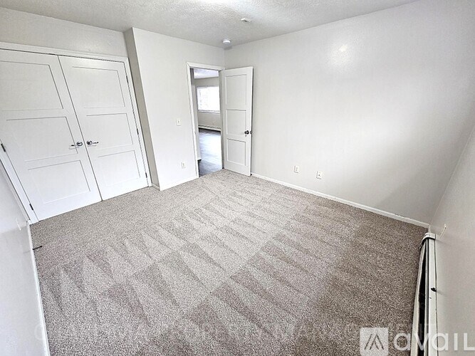 A carpeted room with a door and a window.